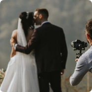 Fotograf uchwycił nowożeńców w intymnym uścisku. Panna młoda ma na sobie białą suknię, a pan młody ciemny garnitur. Scena jest spokojna i romantyczna.